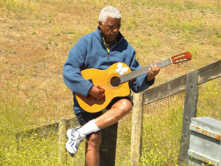 Phil Upchurch playing guitar on fence in country setting